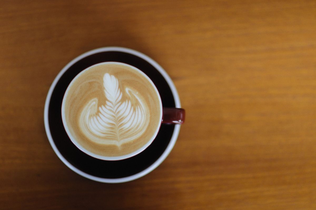 Taza de café con arte latte sobre una mesa de madera